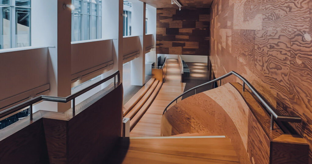 Curved wooden staircase and walkway inside a modern architectural interior.