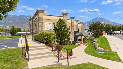 Sidewalk curving around the right side of the building to Cardon Law’s first-floor entrance, marked with an orange arrow.