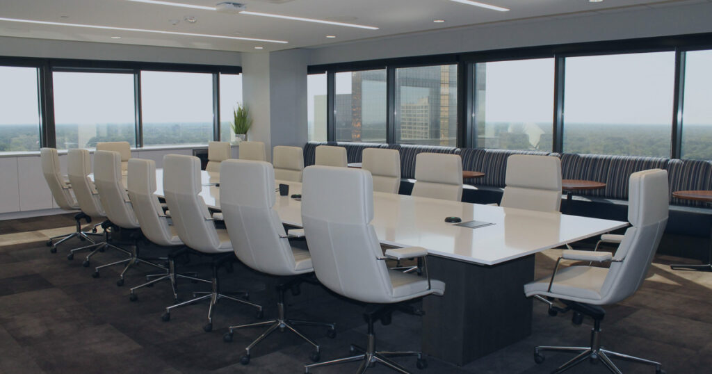 Modern executive boardroom with large windows and conference seating, representing strategic planning before a business sale, succession event, or ownership transition.
