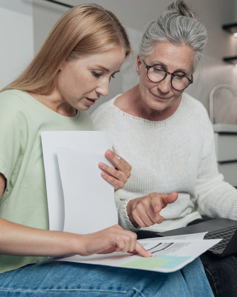 Two family members reviewing financial and trust administration documents together at home.